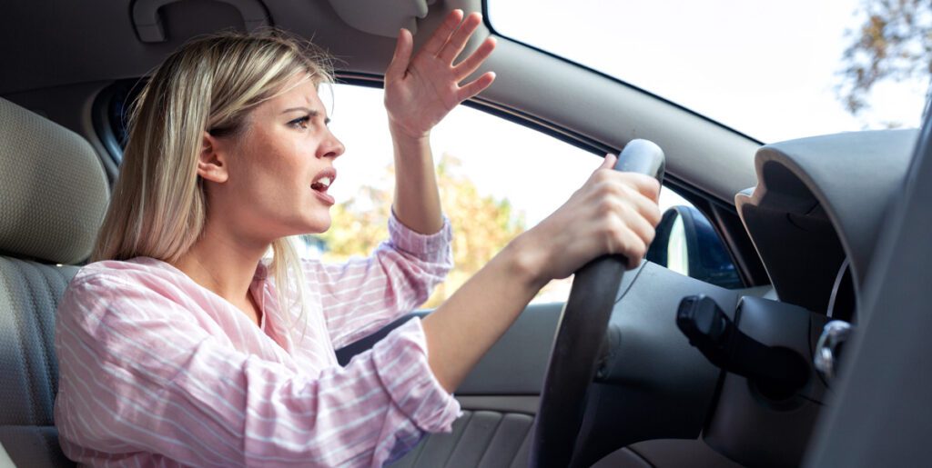 Woman driver showing frustration and anger behind the wheel, common signs of aggressive driving. Anger Management 818.